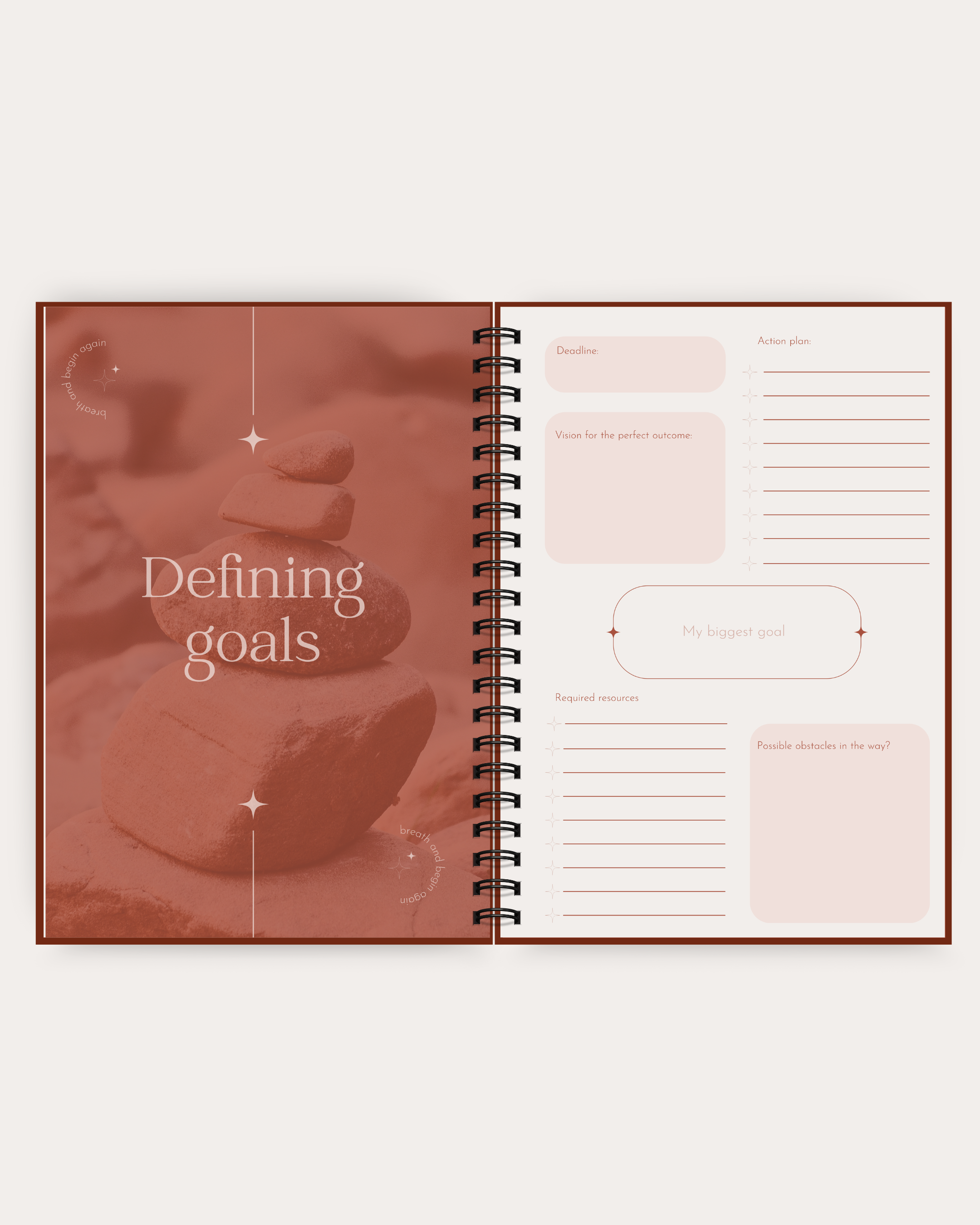 Open spiral-bound planner with 'Defining goals' text on a soft pink background