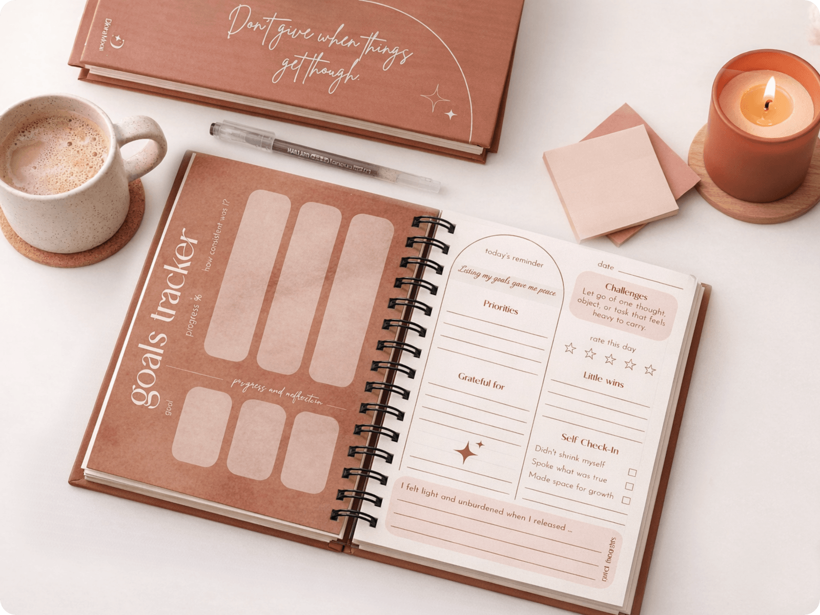 Goals tracker notebook on a table with a cup of coffee and candle