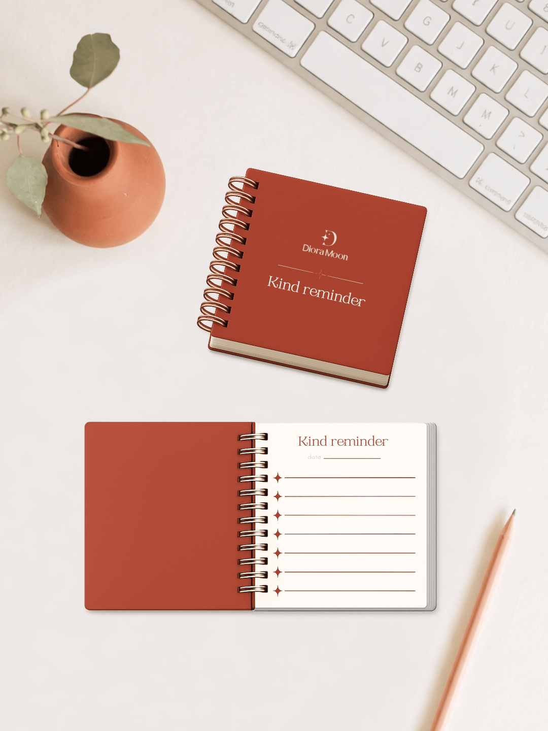 Terracotta notebook with 'Kind reminder' on a white surface with a keyboard and pen.
