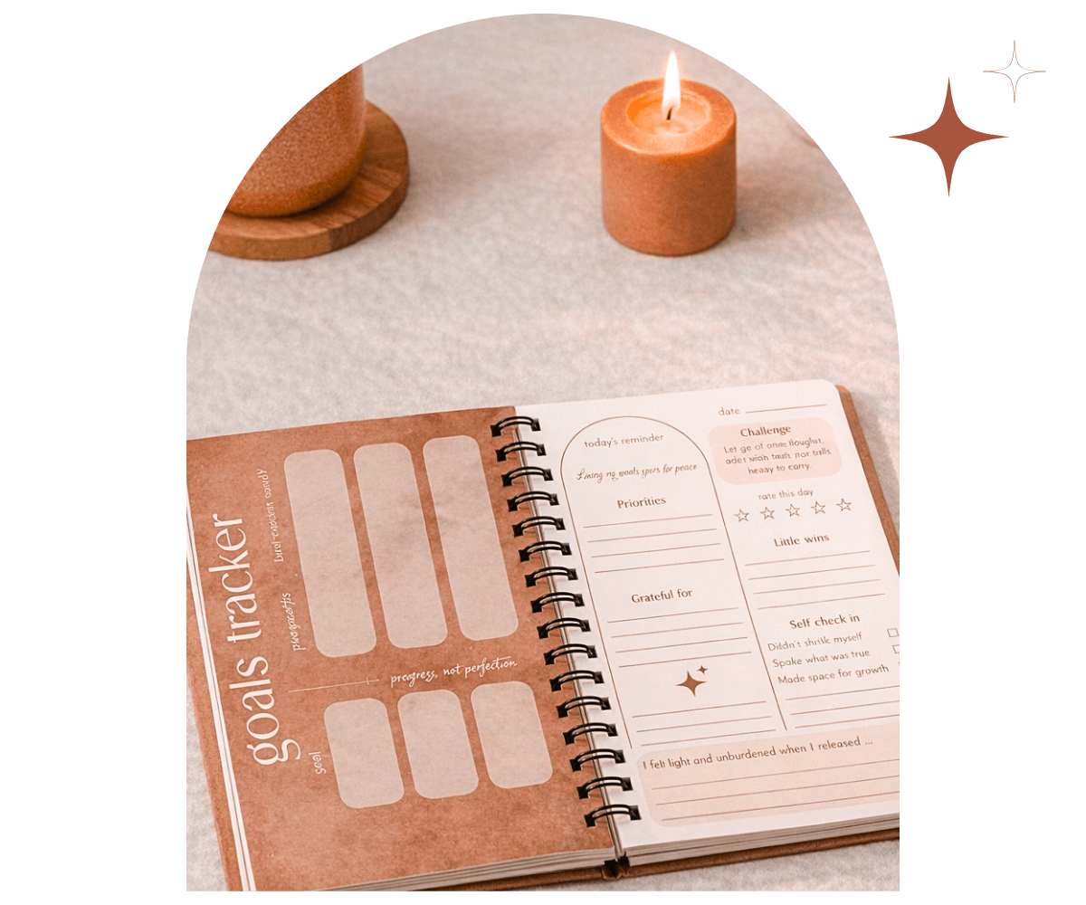 open journal on table with goals tracker page and  candle next to it