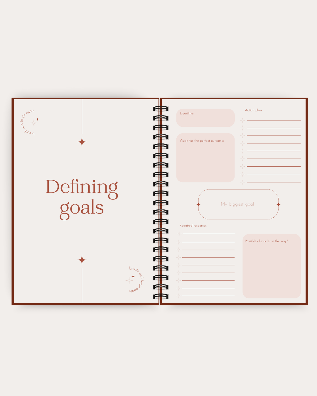 An open spiral-bound planner or notebook with minimalist goal-setting pages, featuring the heading 'Defining goals' in brown text on a cream page, surrounded by pale blush boxes and lines for writing and planning.